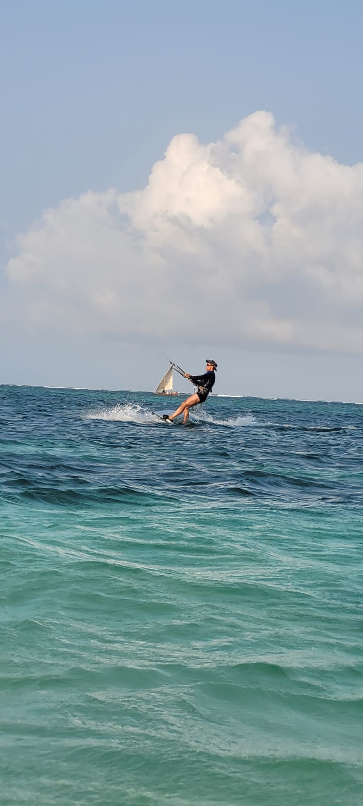 Kitesurfer riding across the deep turquoise water off Diani Beach