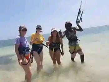 Group of students walking through the shallow water in their harnesses with an instructor