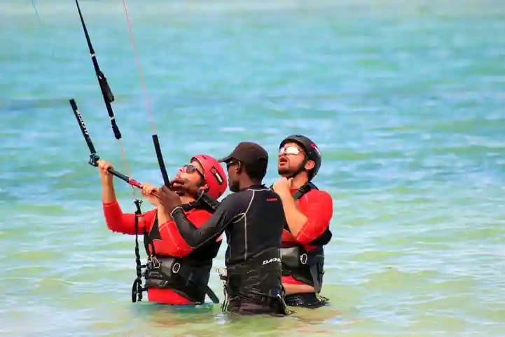 Two students in impact vests learning kite control with an instructor in the lagoon