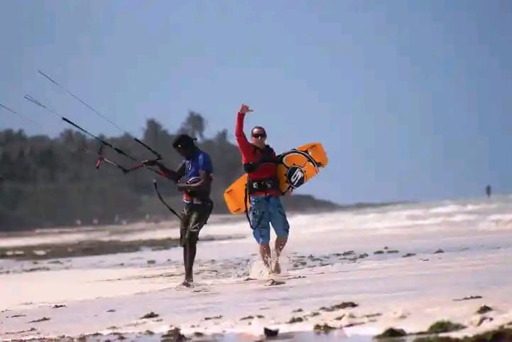 Rider walking along the beach carrying a packed kite after a session