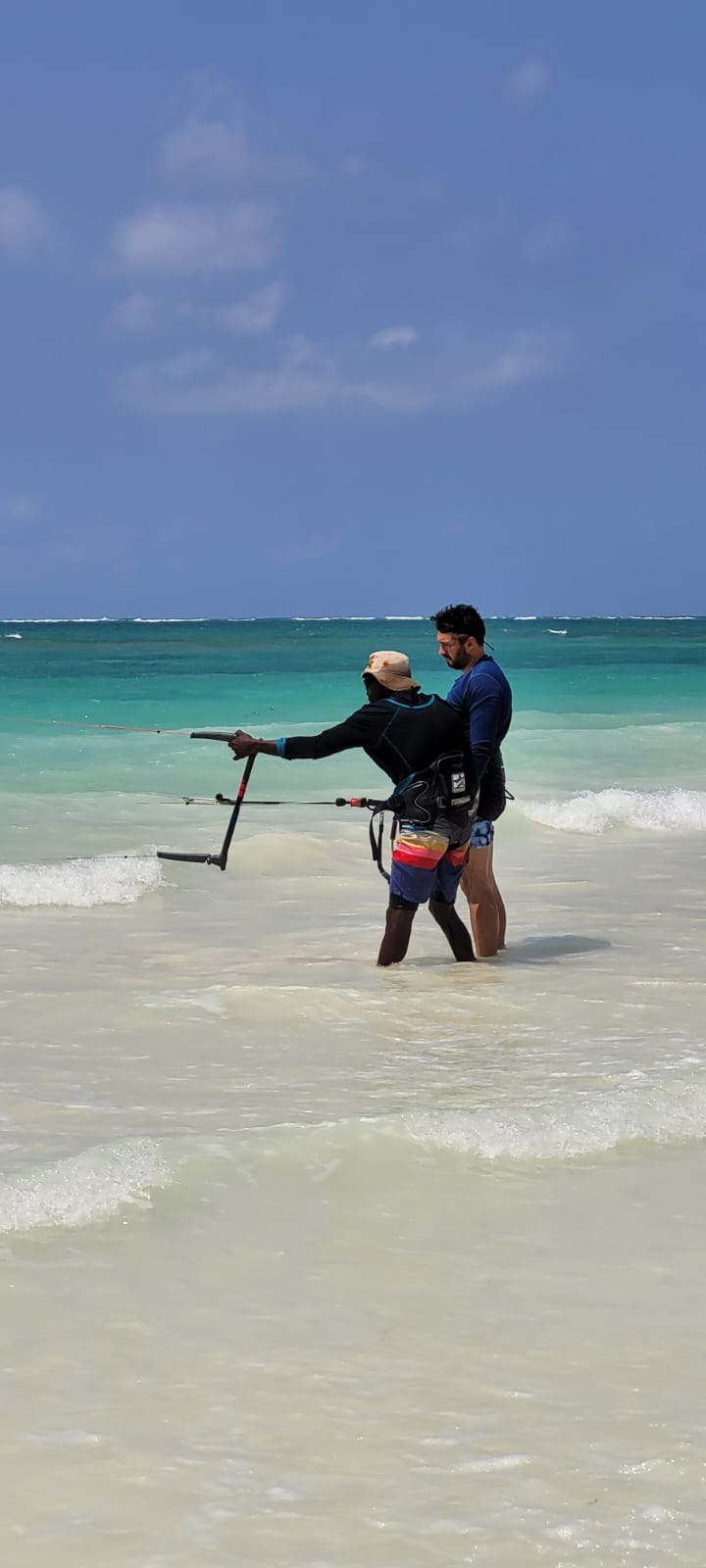 Instructor guiding a student on the control bar in knee-deep water