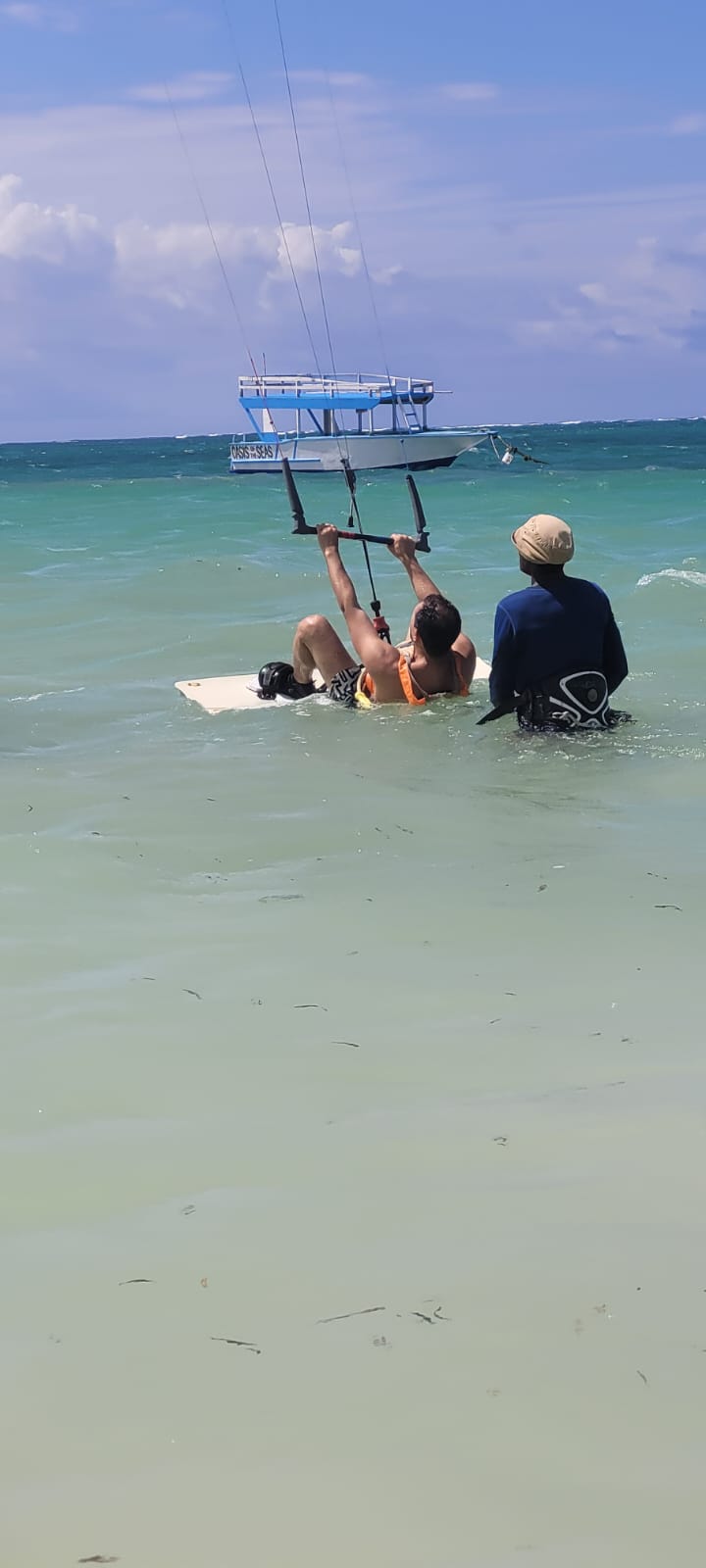 Students sitting in the shallow water practising with the kite alongside their instructor
